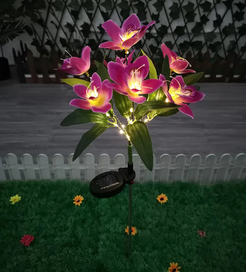 Solar-powered flower light with pink flowers on a grassy area.