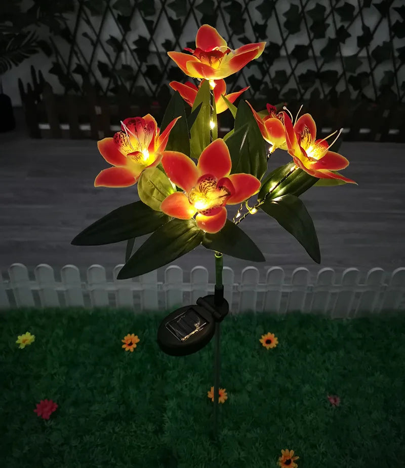 Solar-powered flower light with orange flowers on a grassy area.