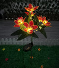 Solar-powered flower light with orange flowers on a grassy area.